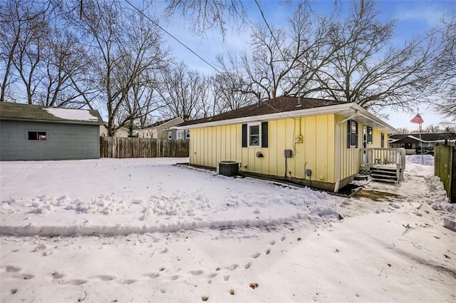 snow covered back of property featuring an outdoor structure