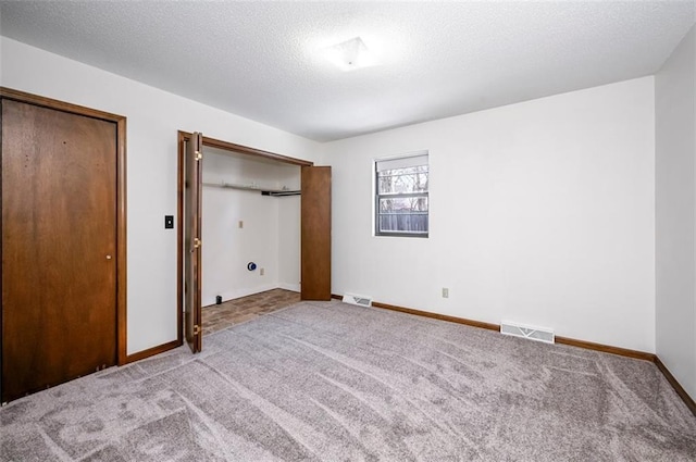 unfurnished bedroom with light colored carpet and a textured ceiling