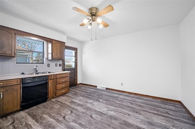 kitchen with sink, backsplash, hardwood / wood-style floors, black dishwasher, and dark brown cabinetry