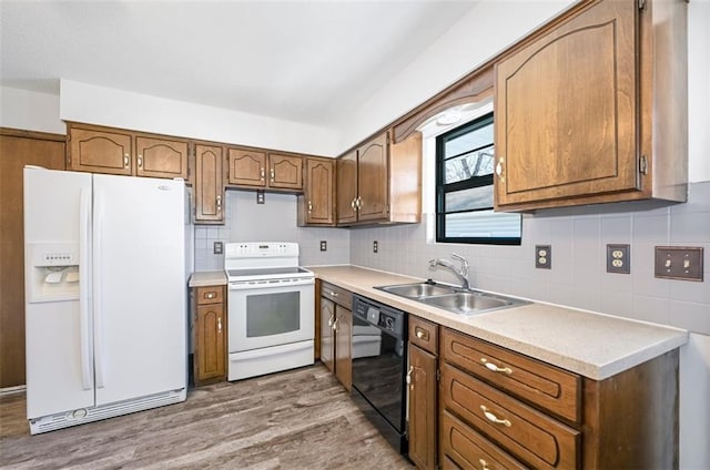 kitchen with tasteful backsplash, sink, white appliances, and light hardwood / wood-style flooring