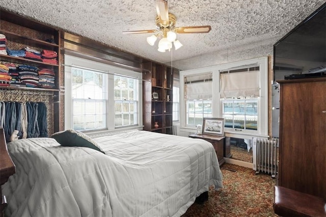 bedroom with a textured ceiling, radiator heating unit, carpet floors, and ceiling fan