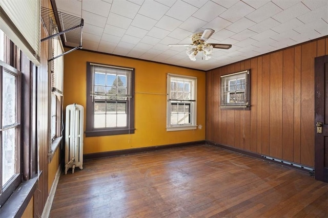 unfurnished room with radiator heating unit, dark wood-type flooring, ceiling fan, and ornamental molding