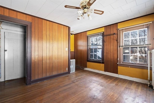 spare room with a healthy amount of sunlight, ornamental molding, dark hardwood / wood-style flooring, and wooden walls