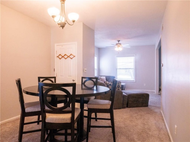 carpeted dining area with ceiling fan with notable chandelier