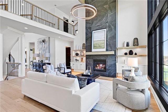 living room with stairs, a high ceiling, wood finished floors, and a high end fireplace