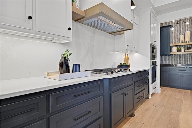 kitchen featuring white cabinets, stainless steel appliances, light countertops, open shelves, and exhaust hood