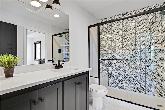 bathroom featuring toilet, tile patterned flooring, a tile shower, and vanity