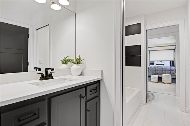 full bathroom with ensuite bath, tile patterned flooring, a washtub, and vanity