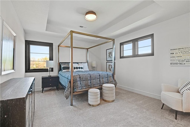 bedroom featuring light carpet, visible vents, baseboards, and a raised ceiling