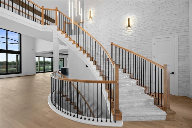 staircase with a towering ceiling and wood finished floors