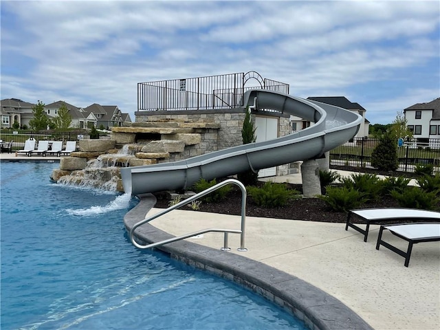 view of swimming pool featuring a residential view, a water slide, fence, and a patio