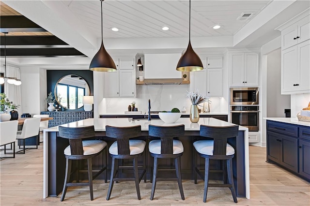 16920 Parkhill St, Overland Park, KS 66221 - kitchen with stainless steel appliances, light countertops, white cabinets, custom range hood, and a breakfast bar