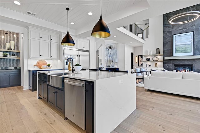 16920 Parkhill St, Overland Park, KS 66221 - kitchen with stainless steel appliances, a sink, open floor plan, light wood finished floors, and white cabinetry