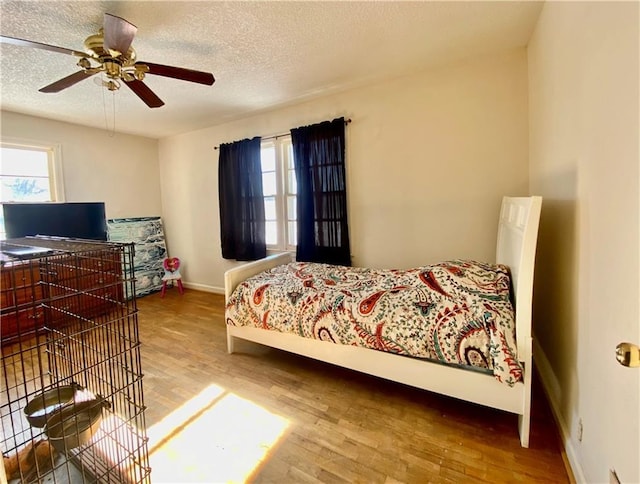 bedroom with hardwood / wood-style flooring, a textured ceiling, and multiple windows