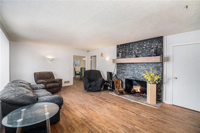 living room with hardwood / wood-style flooring, a tile fireplace, and a textured ceiling