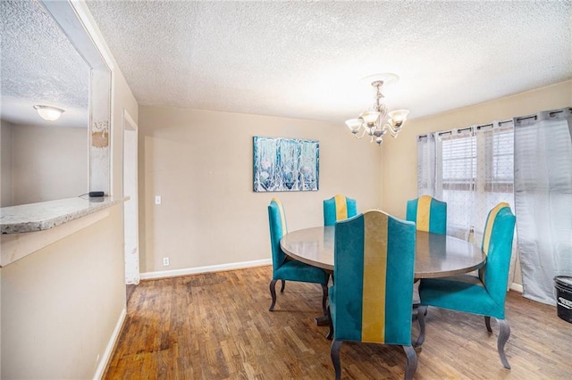 dining room featuring hardwood / wood-style flooring, a textured ceiling, and an inviting chandelier