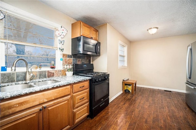 kitchen featuring dark wood-type flooring, sink, stainless steel refrigerator, black gas stove, and backsplash