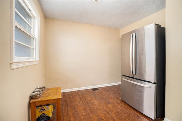 kitchen featuring dark hardwood / wood-style flooring, a textured ceiling, and stainless steel refrigerator