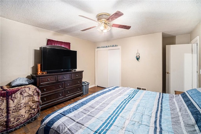 bedroom featuring ceiling fan, dark wood-type flooring, a textured ceiling, and a closet