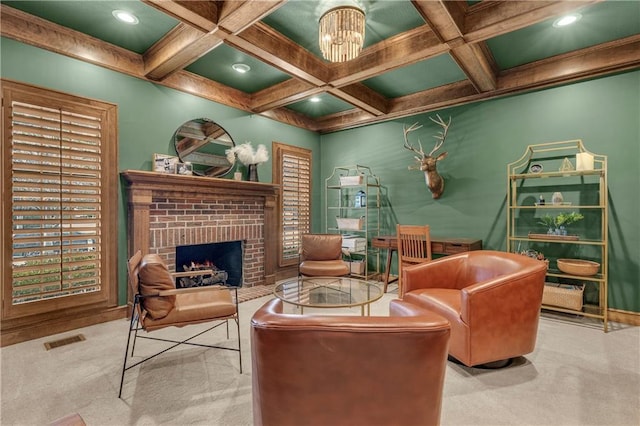 sitting room featuring beamed ceiling, coffered ceiling, a brick fireplace, light carpet, and an inviting chandelier