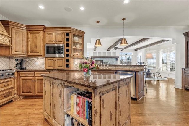 kitchen featuring stainless steel appliances, hanging light fixtures, a center island, and light hardwood / wood-style floors