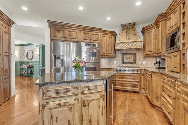 kitchen featuring crown molding, stainless steel appliances, custom exhaust hood, and dark stone counters