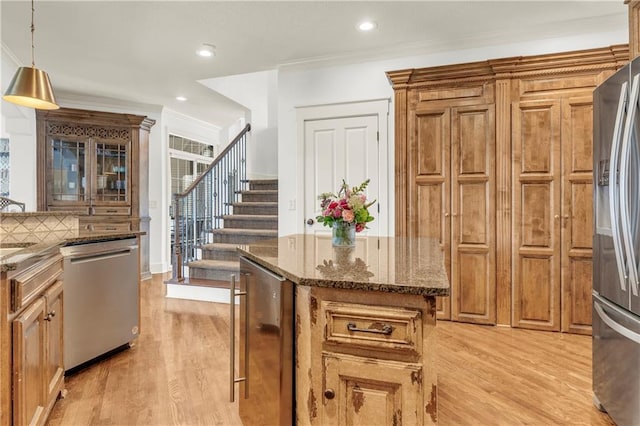 kitchen with stainless steel appliances, ornamental molding, dark stone countertops, and decorative light fixtures