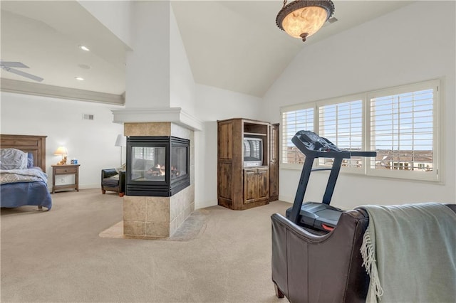 exercise area with light carpet, vaulted ceiling, a tile fireplace, and ceiling fan