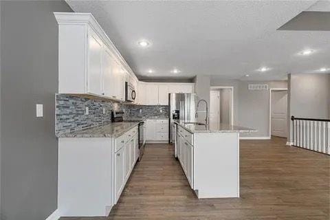 kitchen with stainless steel appliances, white cabinets, sink, and backsplash