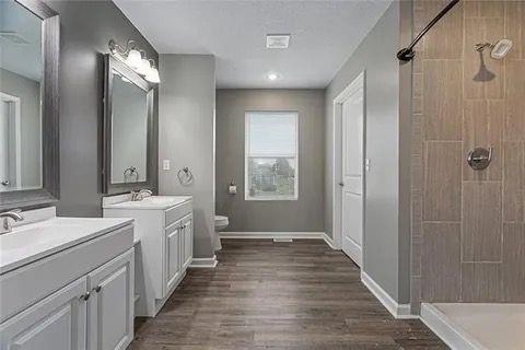 bathroom featuring a tile shower, vanity, toilet, and hardwood / wood-style flooring