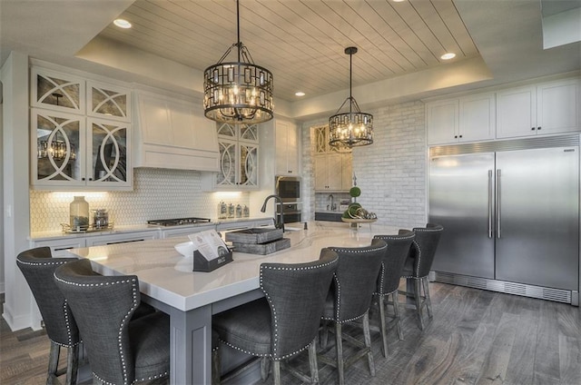 17028 Parkhill St, Overland Park, KS 66221 - kitchen featuring appliances with stainless steel finishes, a chandelier, a raised ceiling, a sink, and dark wood finished floors