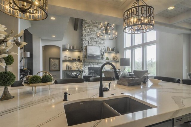 17028 Parkhill St, Overland Park, KS 66221 - kitchen with a chandelier, a sink, a stone fireplace, light stone counters, and recessed lighting