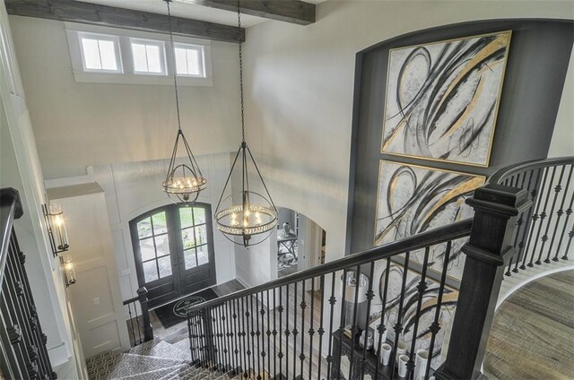 17028 Parkhill St, Overland Park, KS 66221 - stairway with french doors, a high ceiling, a chandelier, arched walkways, and beam ceiling