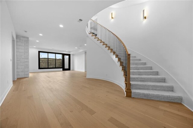17028 Parkhill St, Overland Park, KS 66221 - unfurnished living room featuring light wood-style floors, stairs, recessed lighting, baseboards, and arched walkways