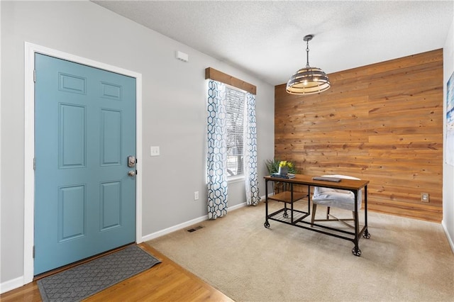 office featuring a textured ceiling, light hardwood / wood-style flooring, and wood walls