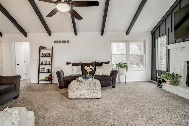 carpeted living room with ceiling fan, a fireplace, and vaulted ceiling with beams