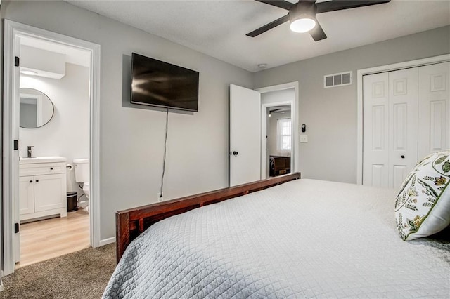 bedroom featuring ensuite bathroom, carpet floors, ceiling fan, and a closet