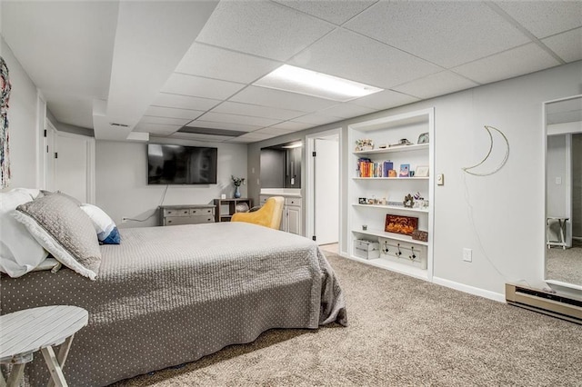 carpeted bedroom with a baseboard radiator and a paneled ceiling