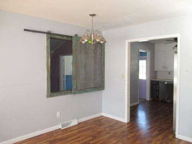 spare room featuring ceiling fan with notable chandelier, a barn door, and dark hardwood / wood-style flooring