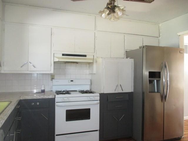 kitchen featuring stainless steel refrigerator with ice dispenser, backsplash, white cabinetry, white range with gas stovetop, and under cabinet range hood