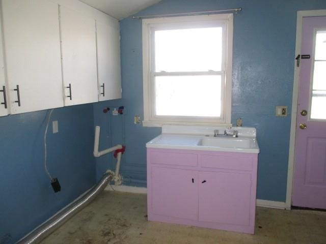 clothes washing area featuring a sink, cabinet space, and baseboards