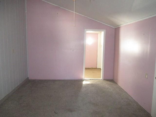 carpeted spare room featuring attic access and vaulted ceiling