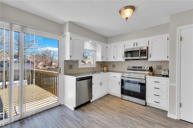 kitchen featuring stainless steel appliances, sink, white cabinets, and backsplash