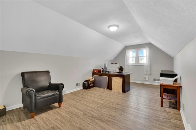 sitting room featuring hardwood / wood-style flooring, lofted ceiling, and a textured ceiling