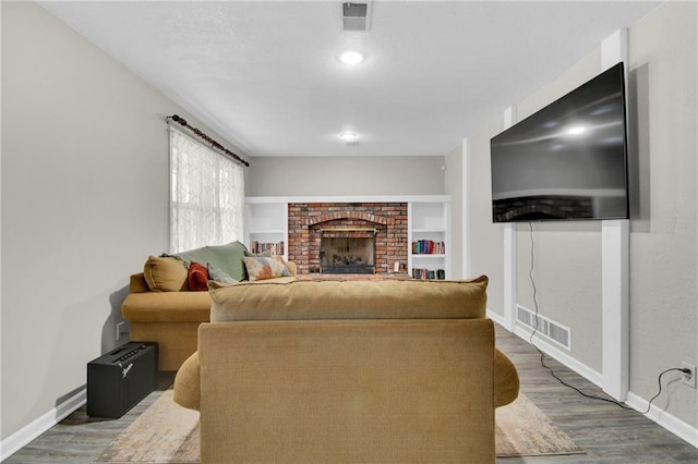 living room with dark hardwood / wood-style flooring, a brick fireplace, and built in features