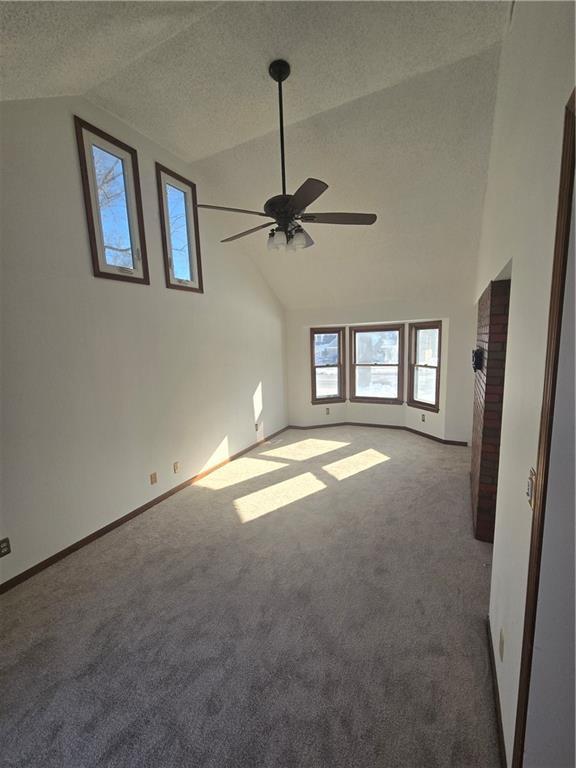 empty room featuring lofted ceiling, a textured ceiling, carpet floors, and ceiling fan