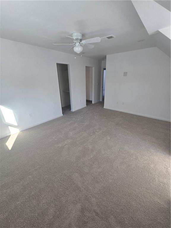 unfurnished room featuring a skylight, ceiling fan, and carpet