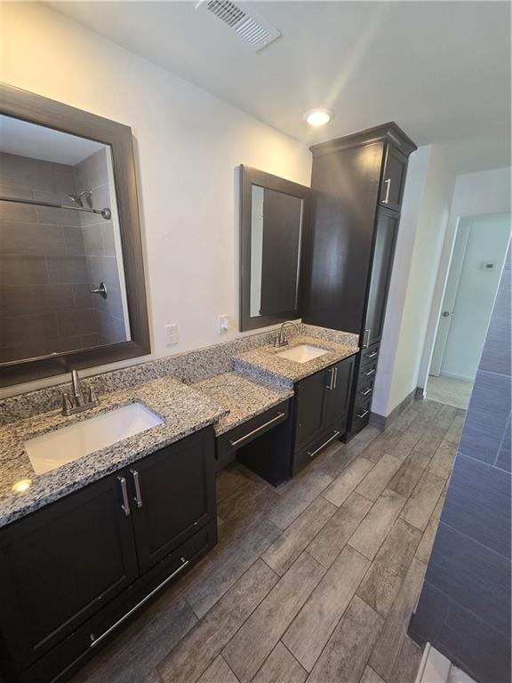 bathroom featuring a tile shower and vanity