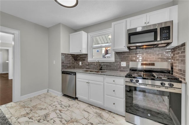 kitchen featuring stainless steel appliances, sink, white cabinetry, tasteful backsplash, and light stone countertops