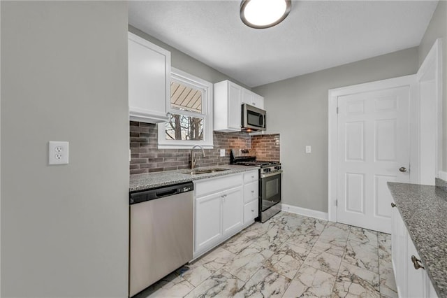 kitchen featuring sink, white cabinets, light stone counters, decorative backsplash, and appliances with stainless steel finishes